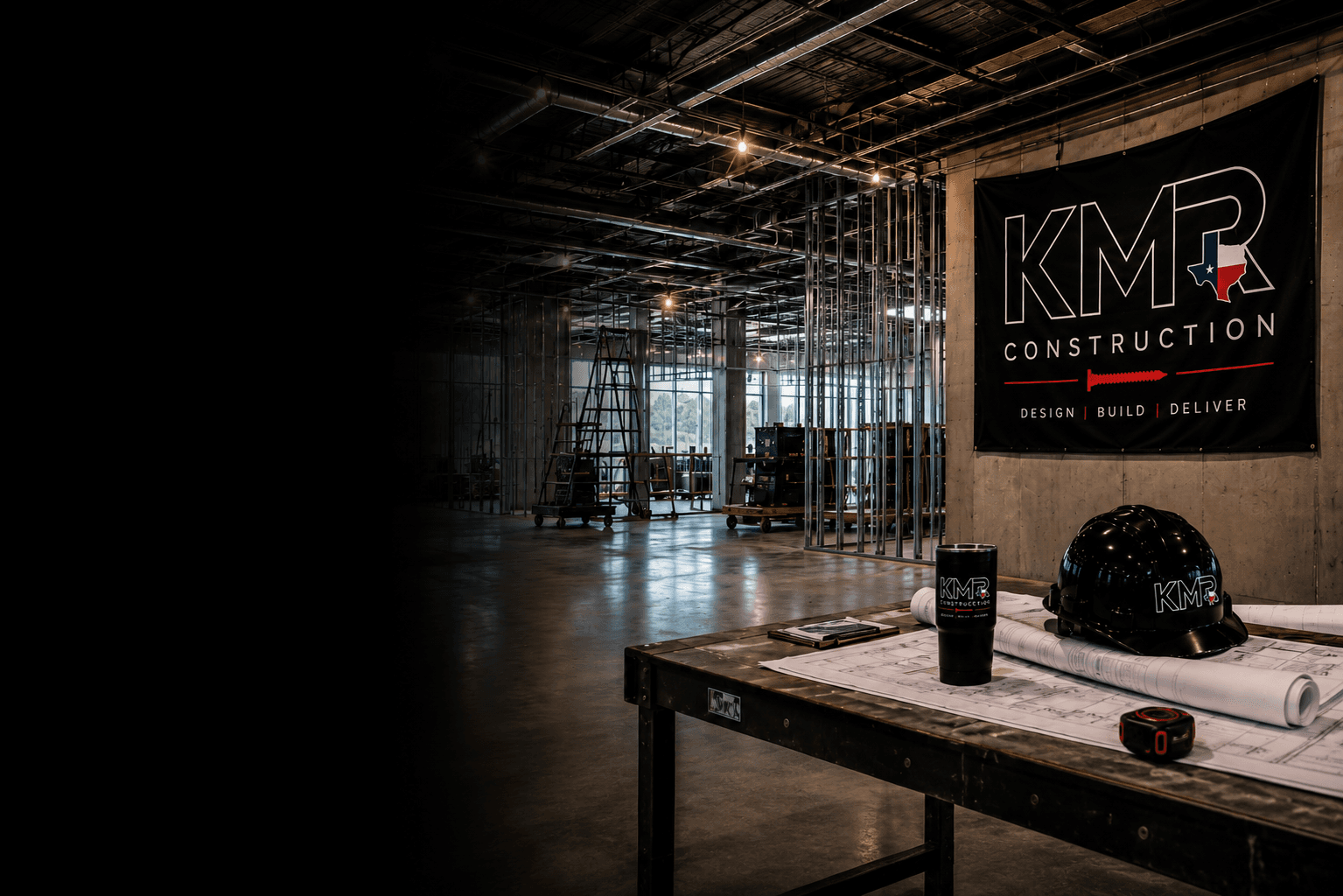 KMR job site interior with metal stud framing, KMR banner, and tool table